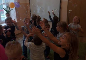 Dzieci łapią puszczane przez animatora bańki mydlane